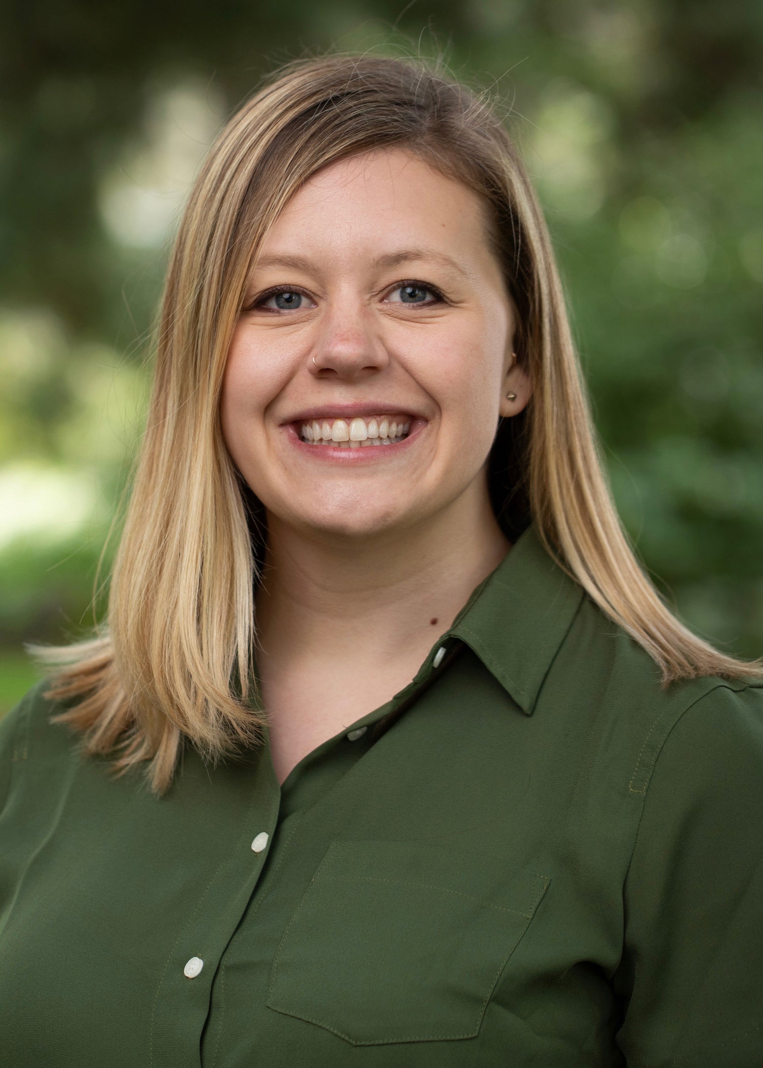 Kate Petcosky-Kulkarni headshot against green outdoor backdrop