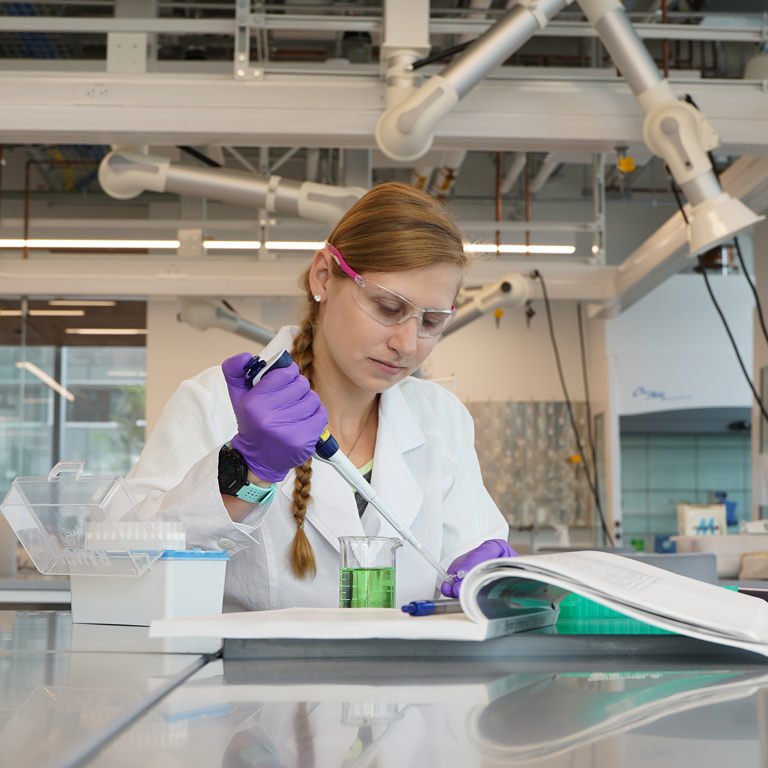 Woman in research lab wearing protective glasses and gloves. 