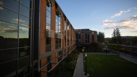 Sunset is reflected in the glass of the brick HEDCO building on the UO campus.