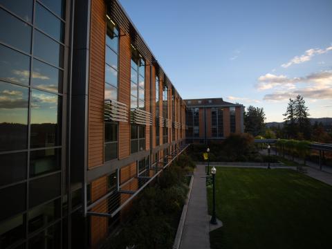 Sunset is reflected in the glass of the brick HEDCO building on the UO campus.