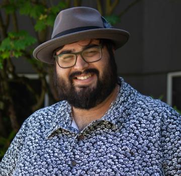 A man wearing a hat and glasses smiling